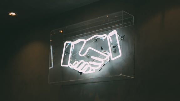 neon sign of handshake sales and customer service language